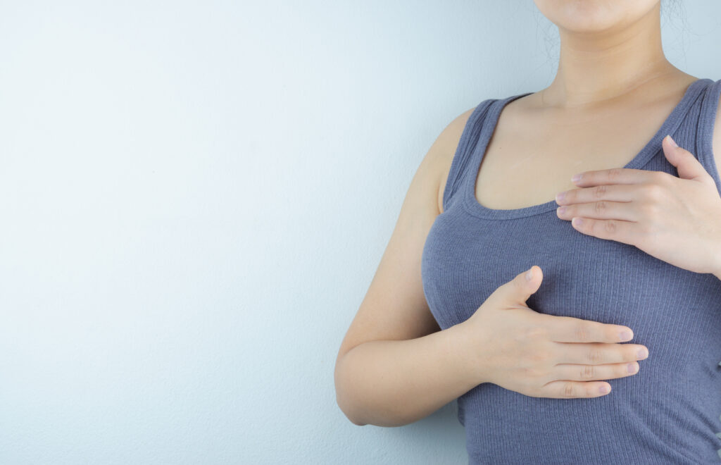 Woman hands doing breast self-exam for checking lumps and signs of breast cancer on white background. Health care and medical concept.