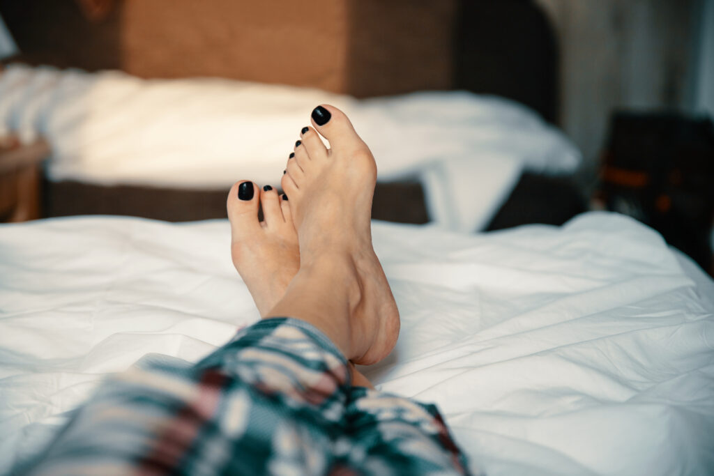 Female relaxing bare foot in bed